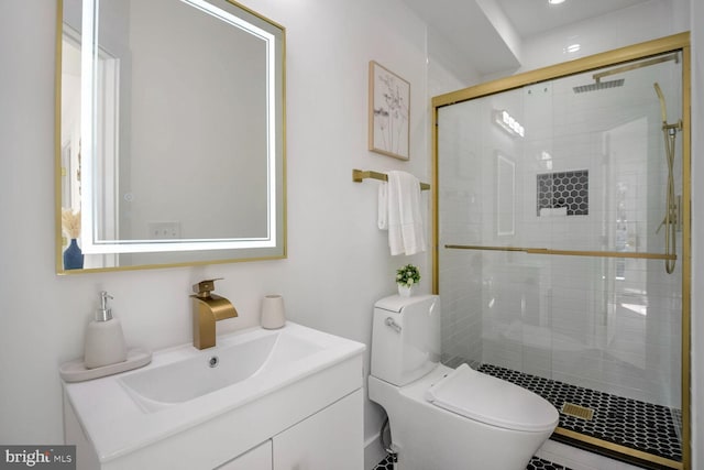 bathroom with a shower with door, vanity, and toilet