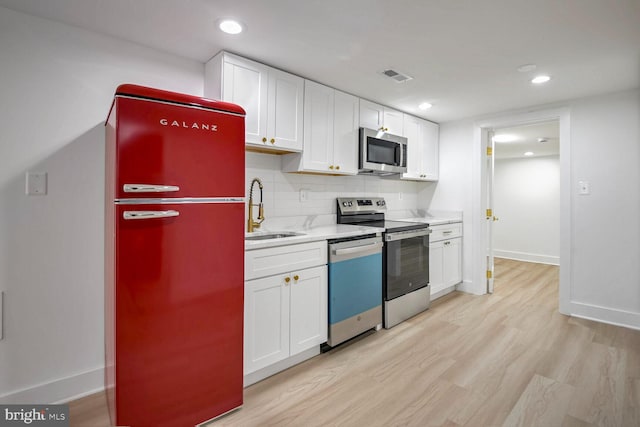 kitchen featuring white cabinets, sink, appliances with stainless steel finishes, and tasteful backsplash