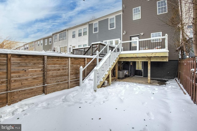 snow covered house with central AC and a wooden deck