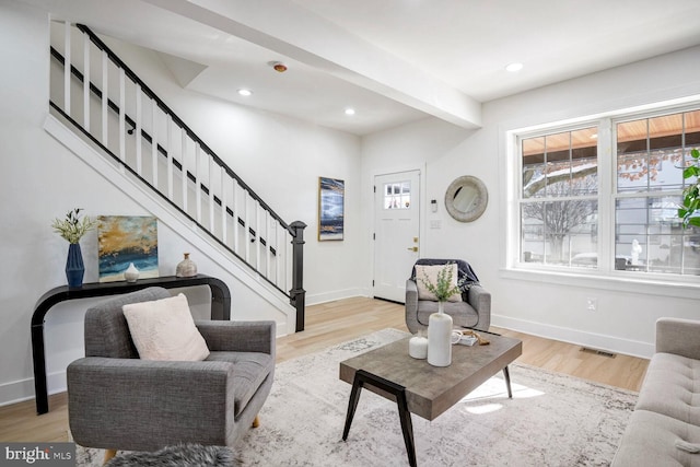 living room with beamed ceiling and light hardwood / wood-style flooring