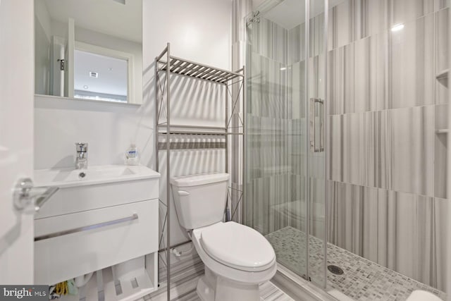 bathroom featuring a shower with door, vanity, and toilet