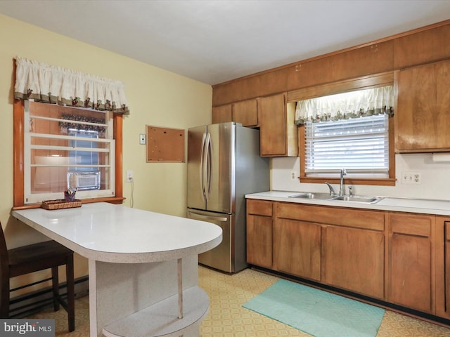 kitchen with stainless steel refrigerator, sink, a baseboard radiator, a kitchen breakfast bar, and kitchen peninsula