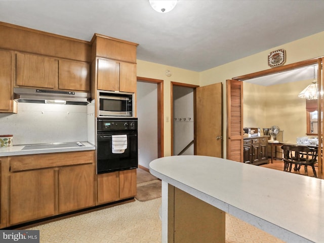 kitchen featuring pendant lighting, black oven, stovetop, and stainless steel microwave