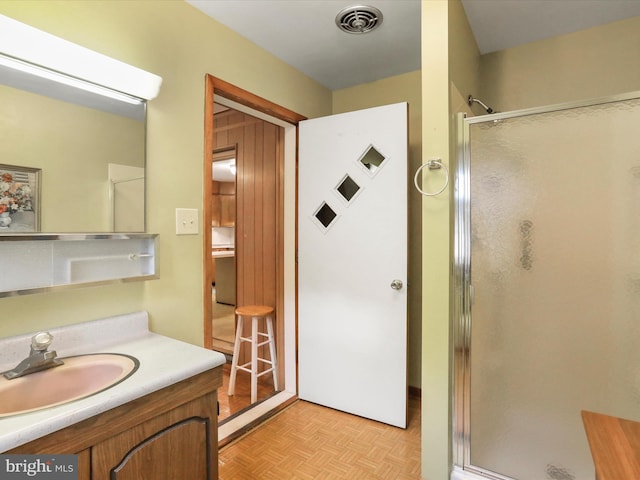 bathroom with vanity, parquet floors, and an enclosed shower