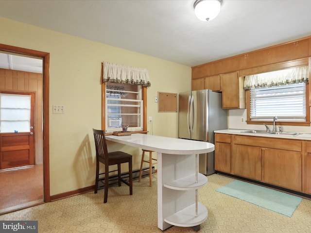 kitchen featuring a kitchen breakfast bar, stainless steel fridge, sink, and baseboard heating