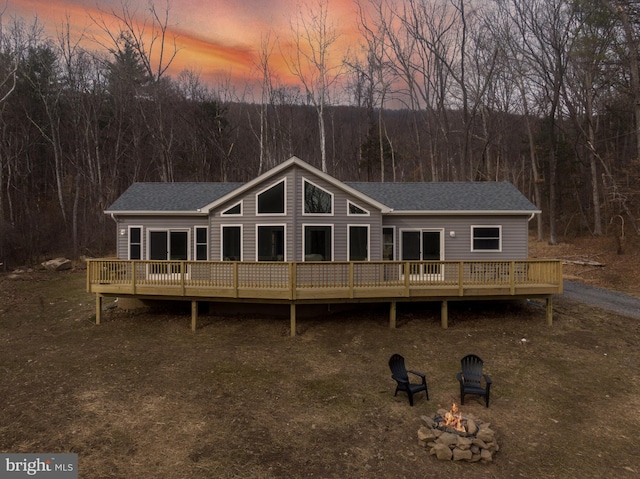 back house at dusk with a fire pit and a deck