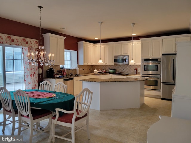 kitchen featuring a healthy amount of sunlight, a kitchen island, hanging light fixtures, and appliances with stainless steel finishes