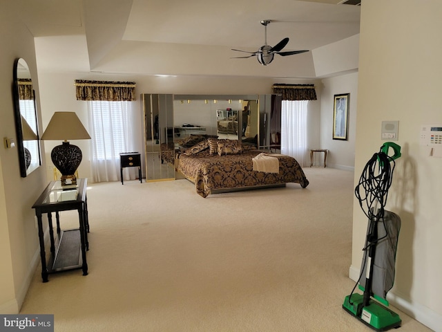 carpeted bedroom with ceiling fan and a tray ceiling