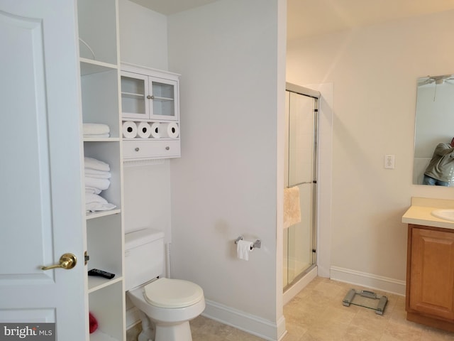 bathroom featuring tile patterned floors, vanity, a shower with shower door, and toilet