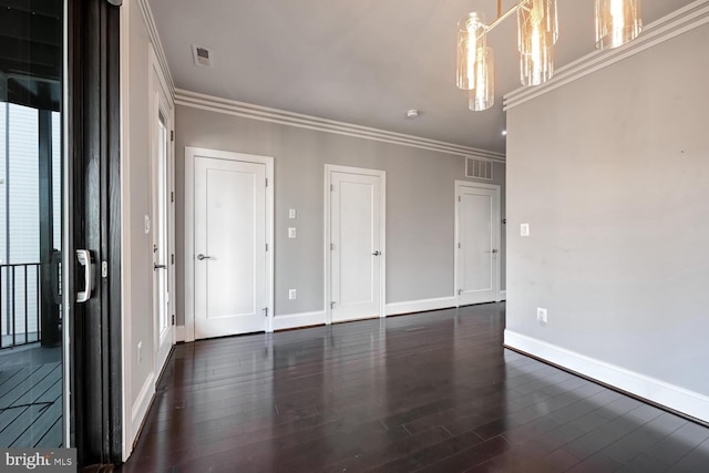 unfurnished room with a chandelier, ornamental molding, and dark wood-type flooring