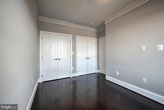 unfurnished bedroom featuring crown molding and dark wood-type flooring