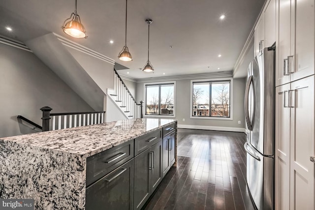 kitchen with a center island, dark hardwood / wood-style floors, stainless steel fridge, light stone countertops, and ornamental molding