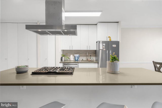 kitchen with a kitchen bar, island exhaust hood, white cabinetry, and appliances with stainless steel finishes