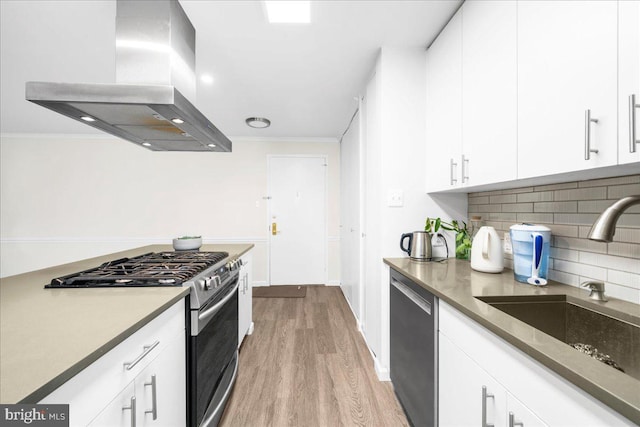 kitchen with white cabinetry, sink, light hardwood / wood-style flooring, extractor fan, and appliances with stainless steel finishes