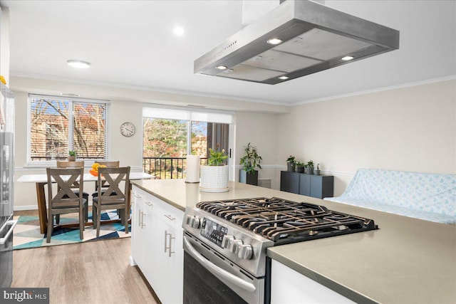 kitchen featuring light hardwood / wood-style floors, white cabinetry, crown molding, and stainless steel stove