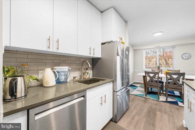 kitchen with stainless steel appliances, white cabinetry, tasteful backsplash, and sink