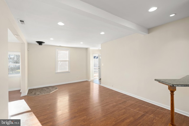 unfurnished living room featuring hardwood / wood-style flooring, beamed ceiling, and a wealth of natural light