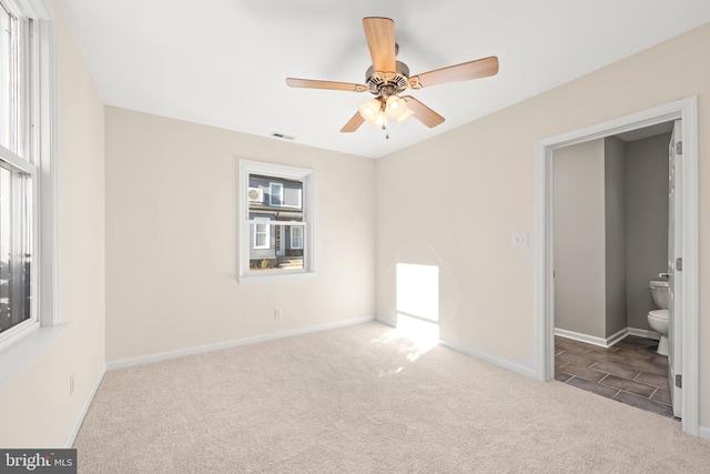 unfurnished bedroom featuring light carpet, ceiling fan, and ensuite bathroom