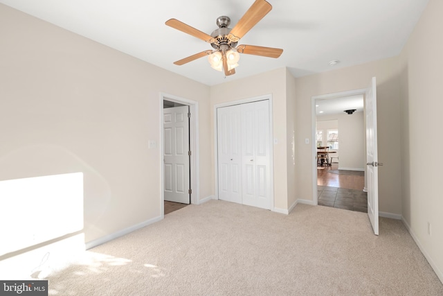 unfurnished bedroom with light colored carpet, a closet, and ceiling fan