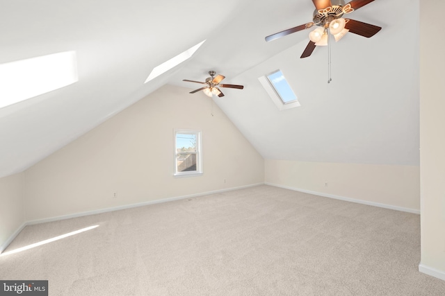 additional living space featuring light colored carpet, ceiling fan, and vaulted ceiling with skylight