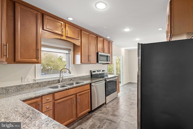 kitchen with light stone countertops, stainless steel appliances, a wealth of natural light, and sink