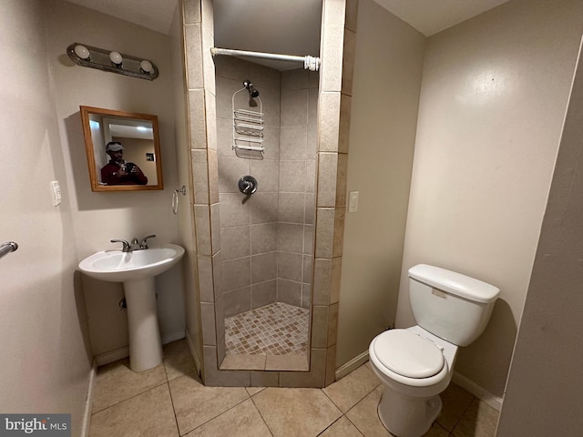 bathroom featuring tile patterned floors, toilet, sink, and a tile shower