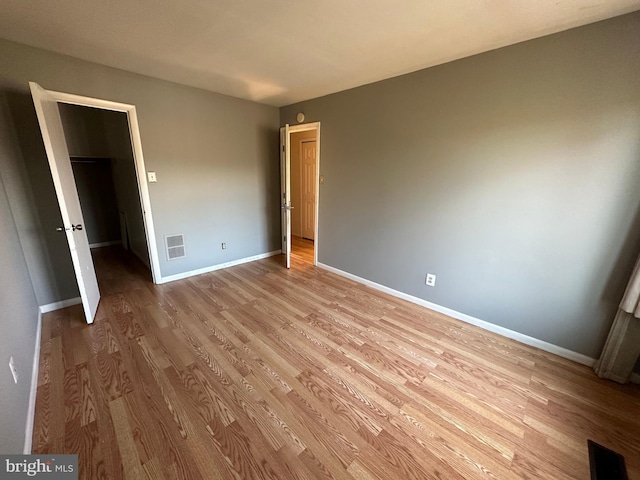 unfurnished bedroom featuring light wood-type flooring and a spacious closet