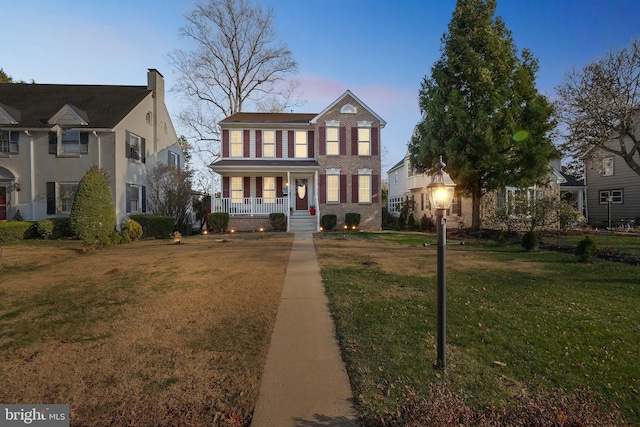 colonial inspired home with a lawn and covered porch