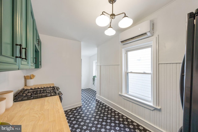 kitchen with pendant lighting, green cabinets, appliances with stainless steel finishes, a wall mounted AC, and a notable chandelier