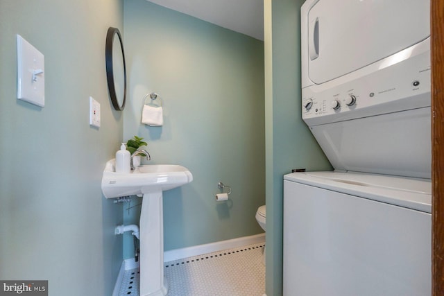 bathroom with toilet and stacked washer / dryer