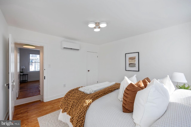 bedroom with hardwood / wood-style flooring and a wall unit AC