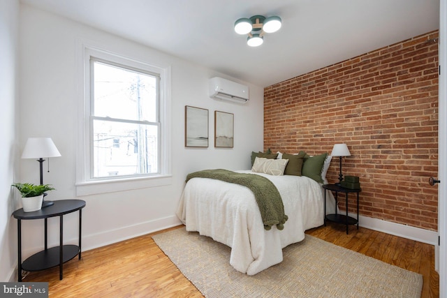 bedroom featuring hardwood / wood-style flooring, brick wall, and a wall mounted AC