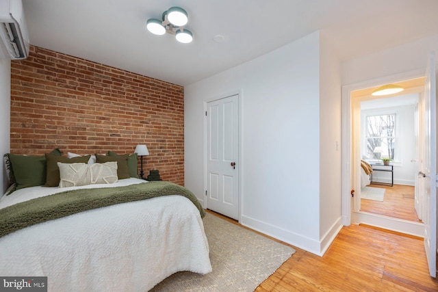 bedroom with hardwood / wood-style flooring, brick wall, and a wall mounted AC