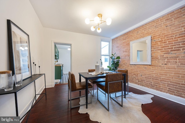 dining space featuring a notable chandelier, dark hardwood / wood-style floors, and brick wall