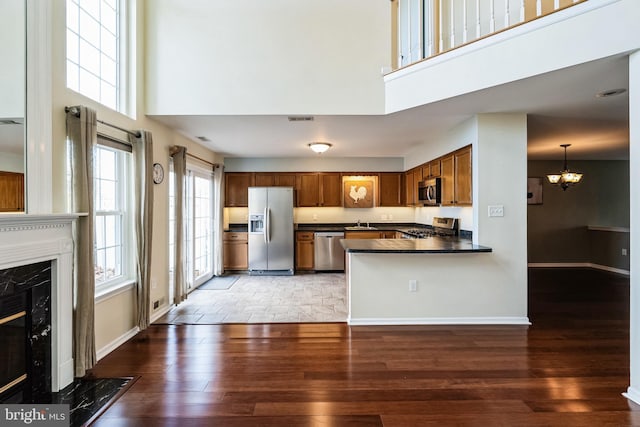 kitchen featuring a high end fireplace, wood-type flooring, stainless steel appliances, and a high ceiling