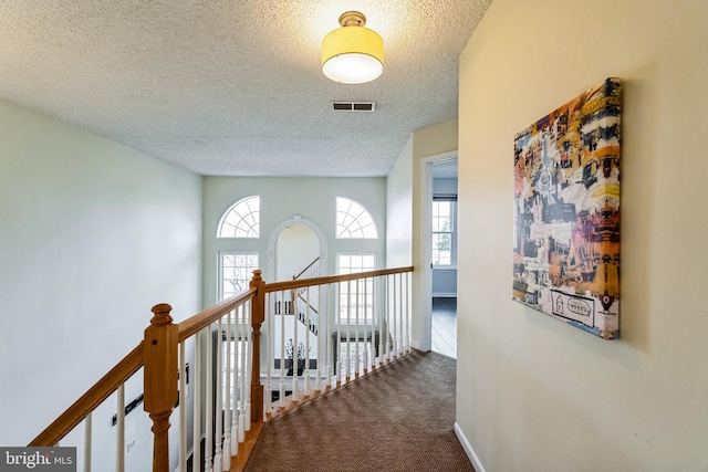 hallway with carpet flooring and a textured ceiling