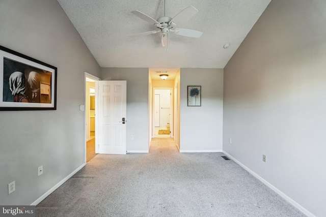 unfurnished bedroom with ceiling fan, light colored carpet, a textured ceiling, and vaulted ceiling