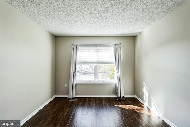 empty room featuring a textured ceiling and dark hardwood / wood-style flooring