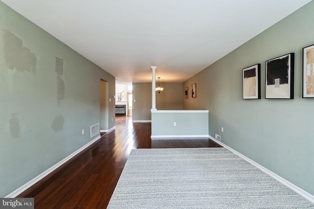 spare room with dark hardwood / wood-style floors and a notable chandelier