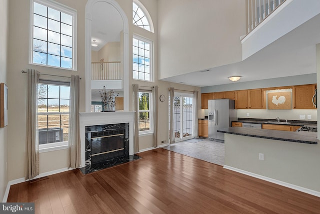 living room with light hardwood / wood-style floors, sink, a towering ceiling, and a fireplace