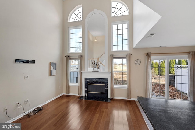 unfurnished living room featuring hardwood / wood-style floors, a towering ceiling, a fireplace, and a wealth of natural light