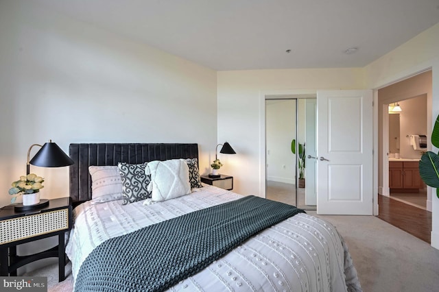 bedroom featuring connected bathroom, light colored carpet, and a closet