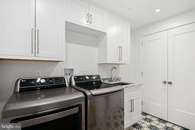 clothes washing area featuring washing machine and clothes dryer, sink, and cabinets