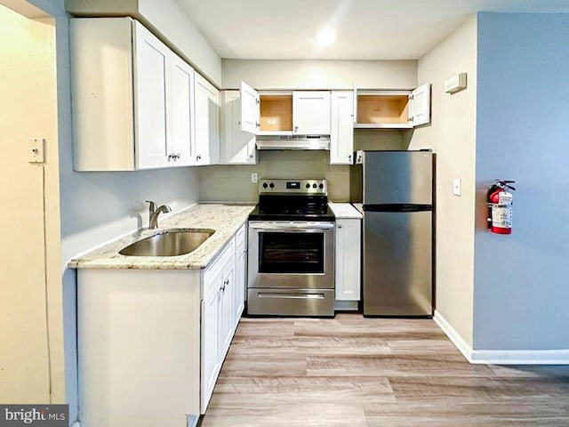 kitchen with exhaust hood, white cabinets, sink, light hardwood / wood-style floors, and stainless steel appliances