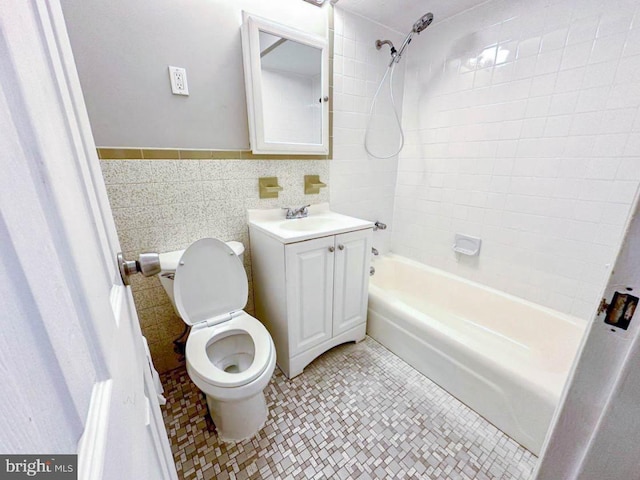 full bathroom featuring vanity, tiled shower / bath combo, tile walls, and toilet