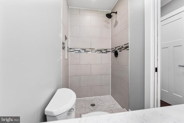 bathroom featuring tiled shower and toilet