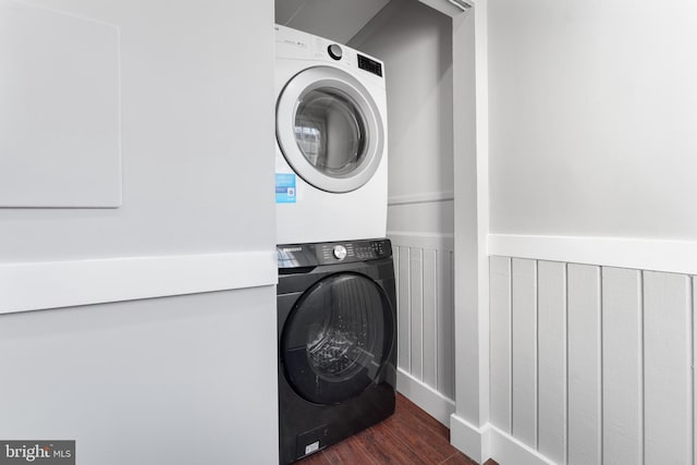 laundry room with dark hardwood / wood-style floors and stacked washer and clothes dryer