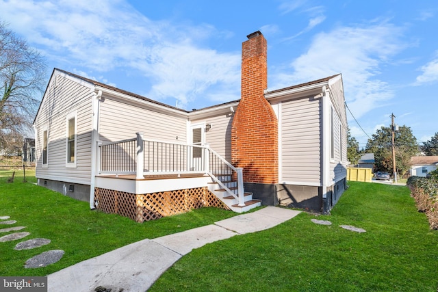 back of property featuring a lawn and a wooden deck