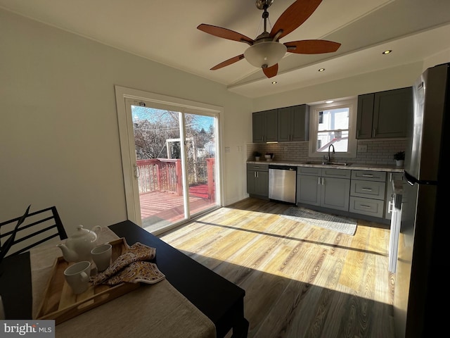 kitchen with gray cabinets, a healthy amount of sunlight, stainless steel appliances, and decorative backsplash