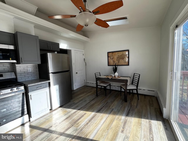 kitchen featuring tasteful backsplash, gray cabinets, light wood-type flooring, and appliances with stainless steel finishes